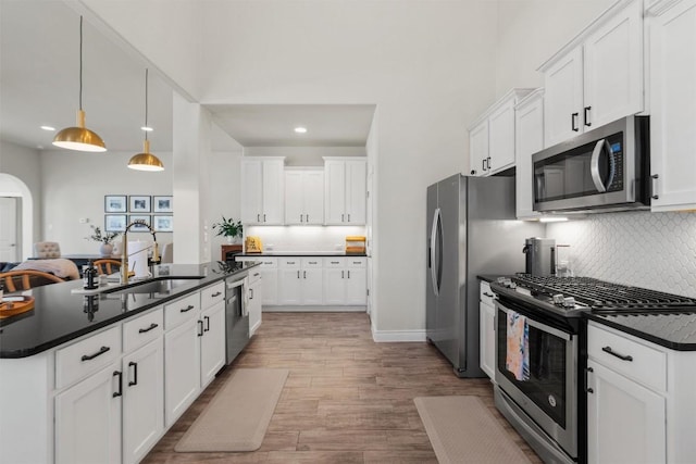 kitchen with sink, decorative light fixtures, stainless steel appliances, and white cabinets