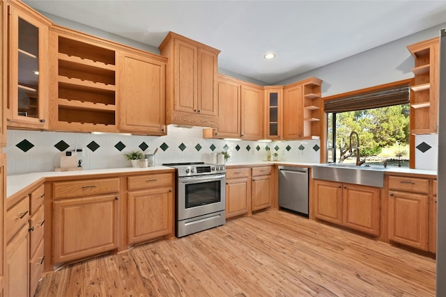 kitchen with stainless steel appliances, light countertops, light wood-style floors, open shelves, and a sink