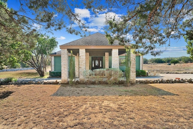 view of front facade featuring stone siding and a shingled roof