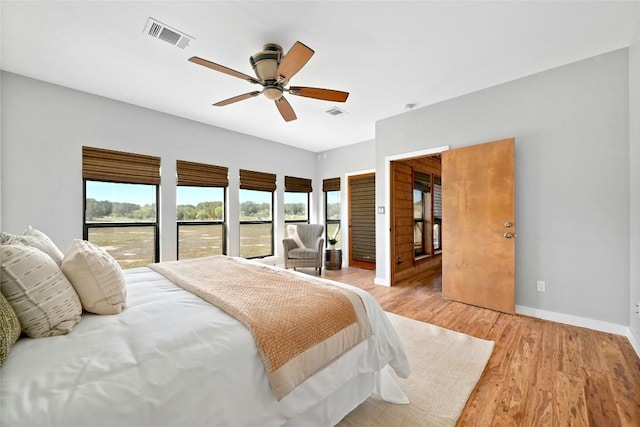 bedroom featuring a ceiling fan, visible vents, light wood-style flooring, and baseboards