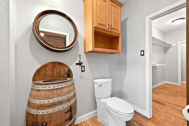 half bath with wood finished floors, toilet, and baseboards