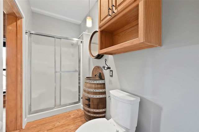 bathroom featuring toilet, a stall shower, and wood finished floors