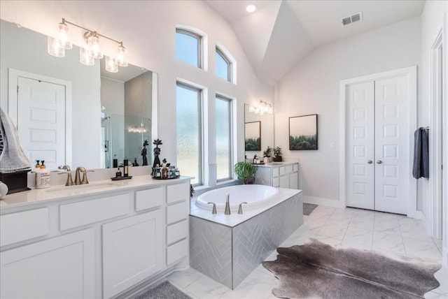 bathroom with vanity, vaulted ceiling, and tiled bath