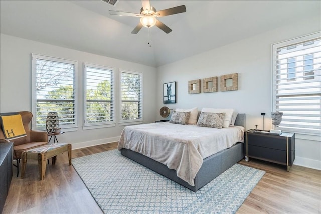 bedroom featuring multiple windows, wood-type flooring, and vaulted ceiling