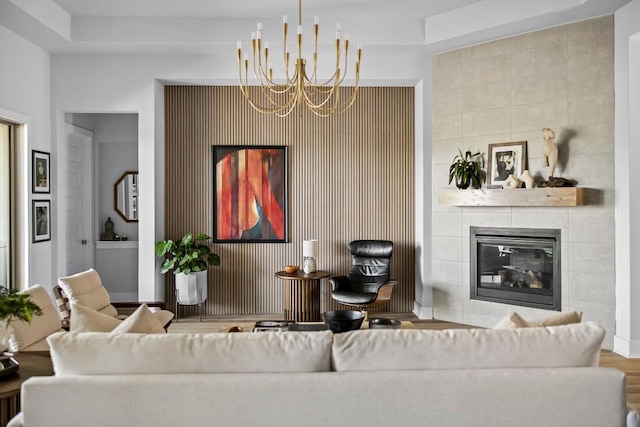 living room with wood-type flooring, a tile fireplace, and a notable chandelier