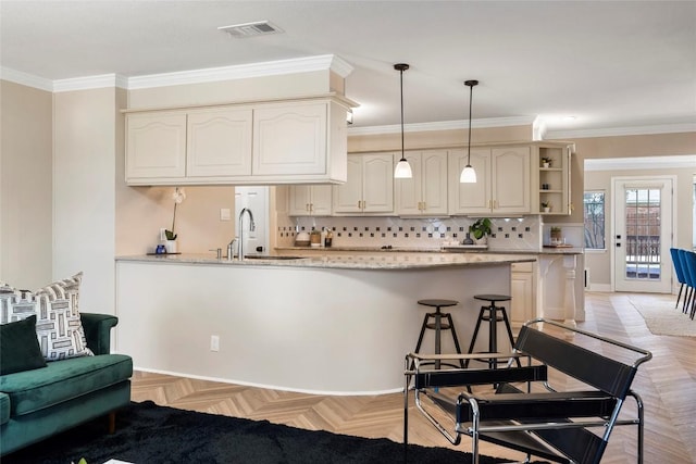 kitchen with light parquet floors, cream cabinetry, light stone counters, and decorative light fixtures