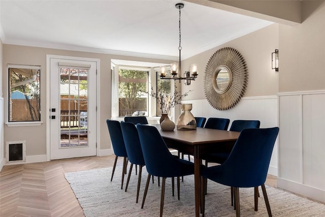 dining room with ornamental molding, parquet flooring, and a chandelier