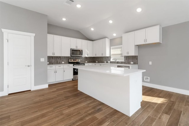 kitchen with a center island, dark hardwood / wood-style flooring, white cabinets, stainless steel appliances, and backsplash