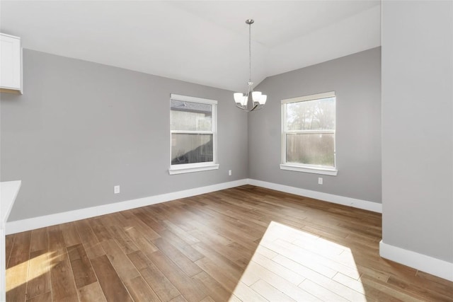 unfurnished dining area with lofted ceiling, light hardwood / wood-style floors, and a chandelier