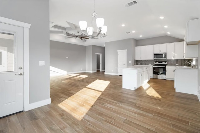 kitchen featuring white cabinets, backsplash, hanging light fixtures, a center island, and stainless steel appliances