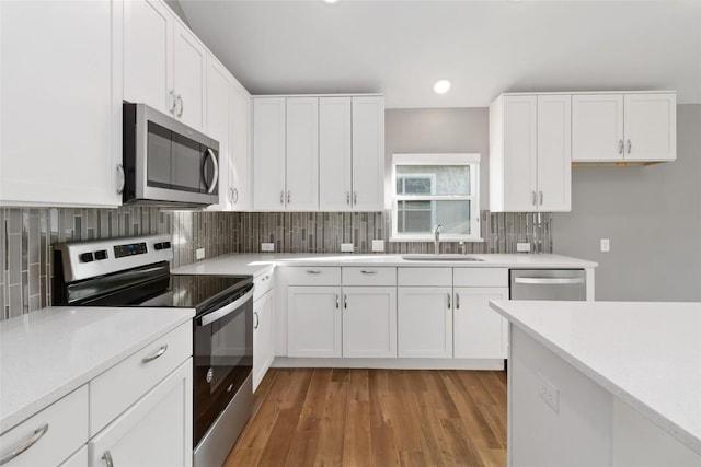 kitchen with sink, white cabinetry, light wood-type flooring, stainless steel appliances, and decorative backsplash