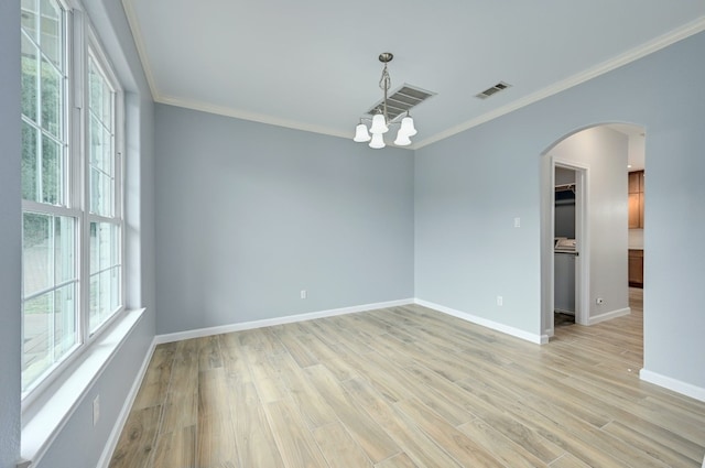 spare room featuring crown molding, a chandelier, and light hardwood / wood-style flooring