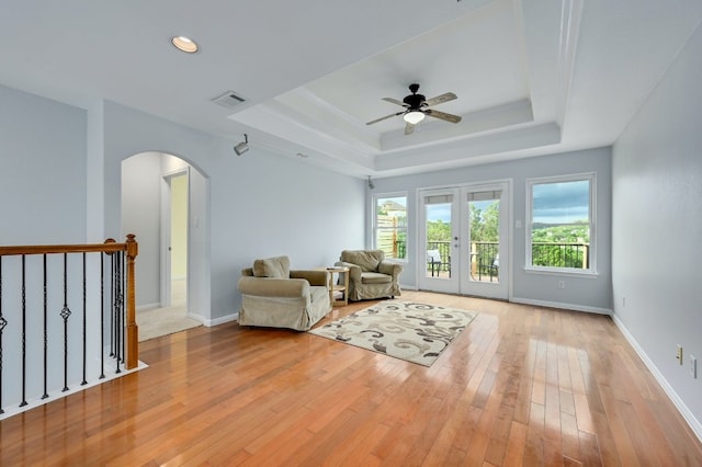 unfurnished room featuring light hardwood / wood-style flooring, a raised ceiling, ceiling fan, and french doors