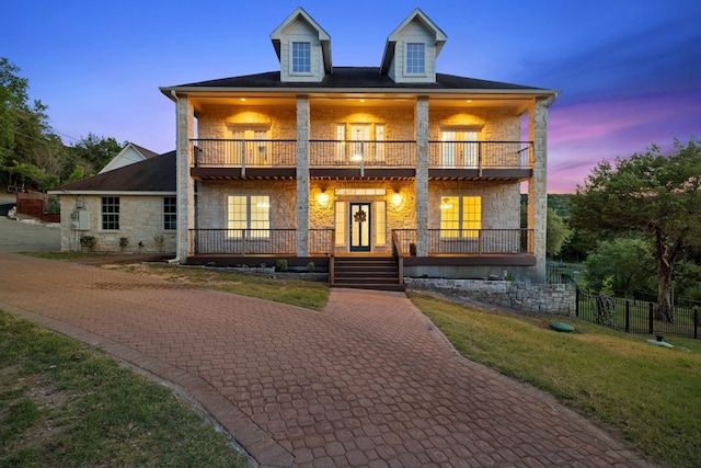 view of front of home featuring a lawn, a balcony, and a porch