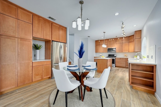 dining space with sink, a chandelier, and light wood-type flooring