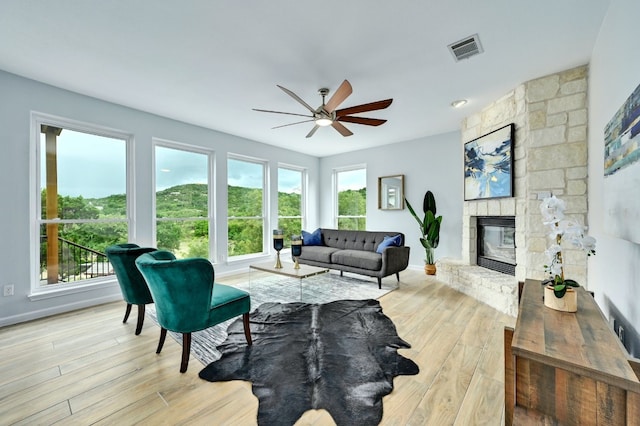 living room with a fireplace, a wealth of natural light, light hardwood / wood-style floors, and ceiling fan