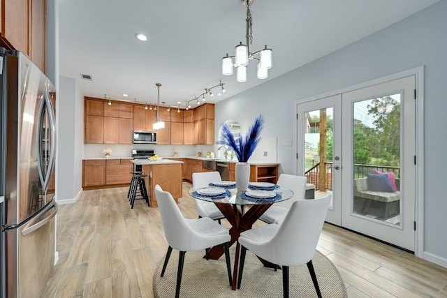 dining room with sink, a chandelier, light hardwood / wood-style floors, and french doors