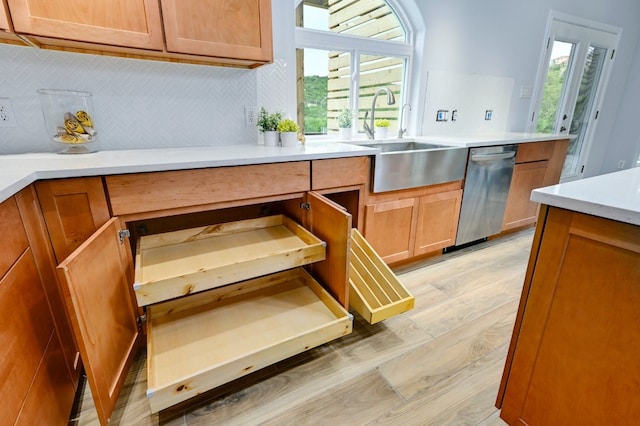 kitchen featuring sink, decorative backsplash, stainless steel dishwasher, and light hardwood / wood-style floors