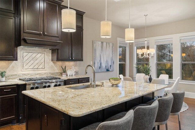 905 Madison Fork Dr, Lakeway, TX 78738 - kitchen featuring tasteful backsplash, wood finished floors, light stone countertops, a center island with sink, and a breakfast bar area