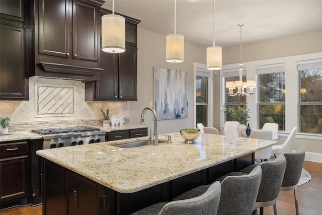 905 Madison Fork Dr, Lakeway, TX 78738 - kitchen featuring decorative backsplash, wood finished floors, light stone counters, a kitchen bar, and a center island with sink