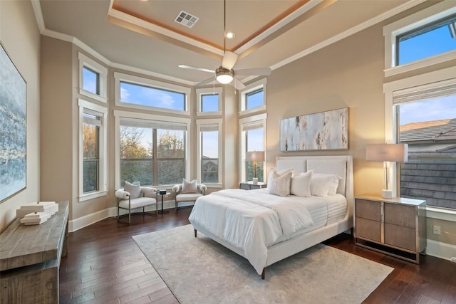 bedroom with dark hardwood / wood-style flooring, a tray ceiling, ornamental molding, and a towering ceiling