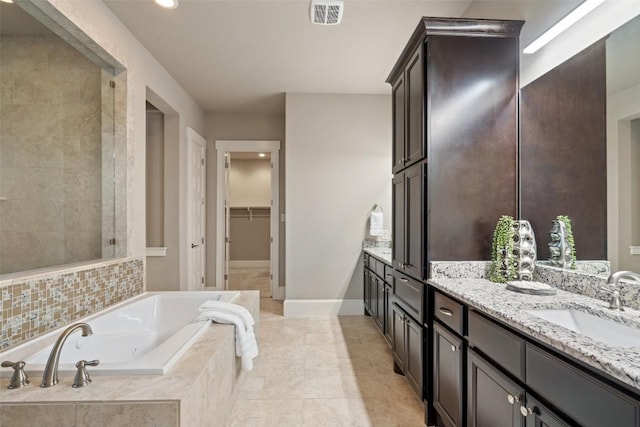 bathroom featuring vanity, tile patterned floors, and tiled bath