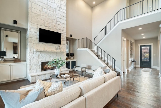 905 Madison Fork Dr, Lakeway, TX 78738 - living room featuring a stone fireplace, dark wood-style floors, stairway, and a high ceiling