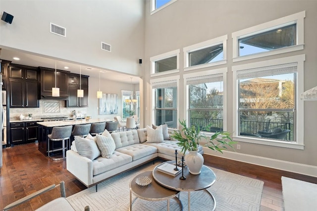 living room featuring a towering ceiling, dark hardwood / wood-style flooring, and a wealth of natural light