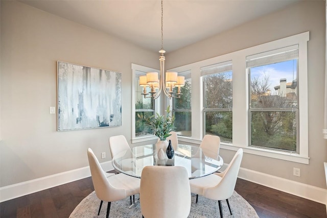 dining area with dark wood-type flooring and a chandelier