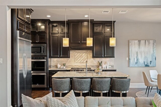 905 Madison Fork Dr, Lakeway, TX 78738 - kitchen with appliances with stainless steel finishes, an island with sink, tasteful backsplash, light stone counters, and recessed lighting