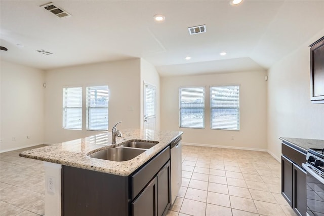 kitchen with light tile patterned flooring, an island with sink, sink, and a wealth of natural light