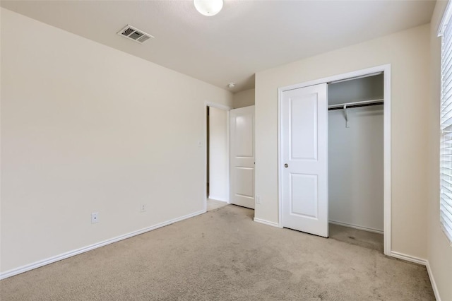 unfurnished bedroom with light carpet and a closet