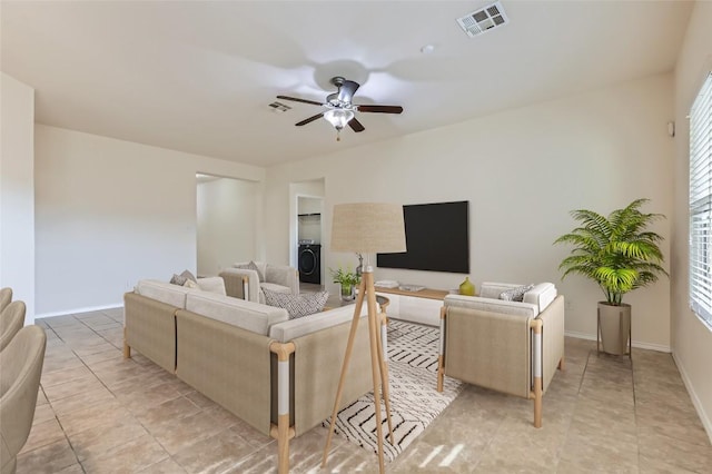 living room with ceiling fan, washer / dryer, and light tile patterned floors