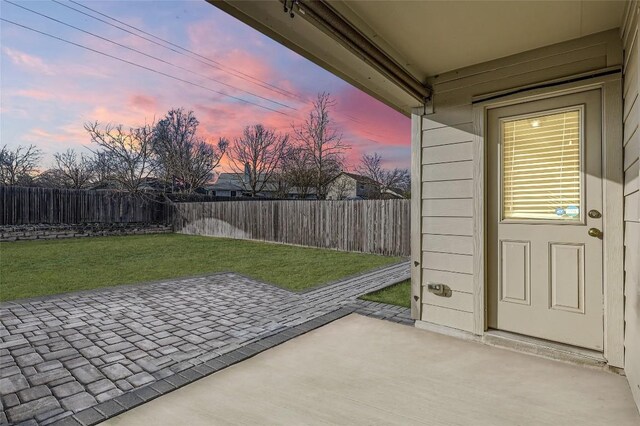 patio terrace at dusk featuring a lawn