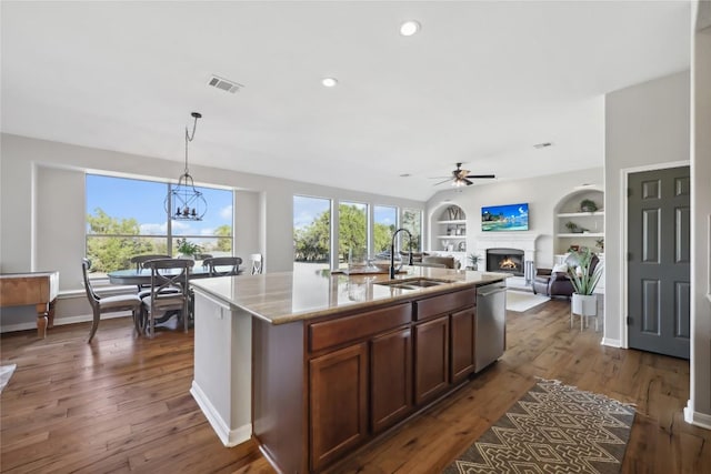 kitchen featuring sink, dishwasher, a kitchen island with sink, light stone countertops, and decorative light fixtures