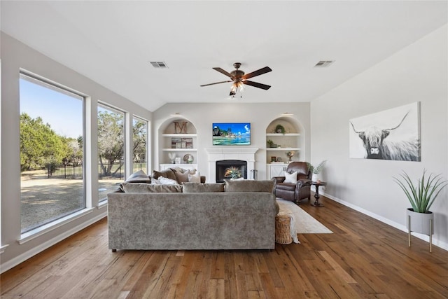 living room featuring wood-type flooring, built in features, and ceiling fan