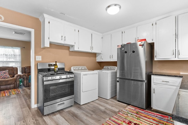 kitchen featuring washing machine and clothes dryer, stainless steel appliances, light hardwood / wood-style floors, and white cabinets