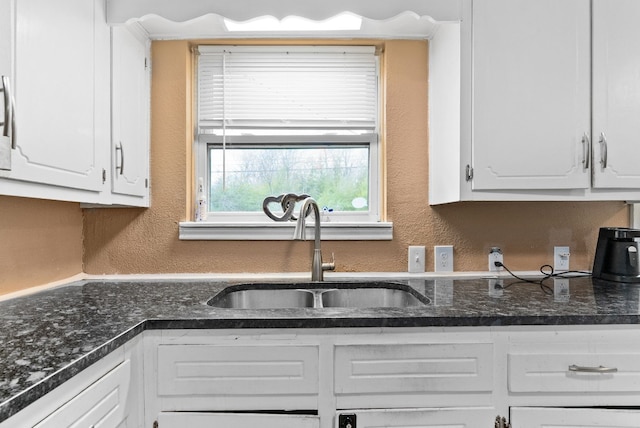 kitchen with white cabinetry, sink, and dark stone countertops