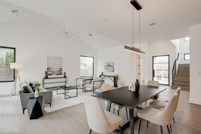 dining room featuring ceiling fan, high vaulted ceiling, and light hardwood / wood-style flooring