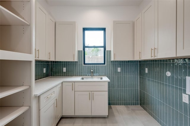 clothes washing area with tile walls, sink, and light tile patterned floors