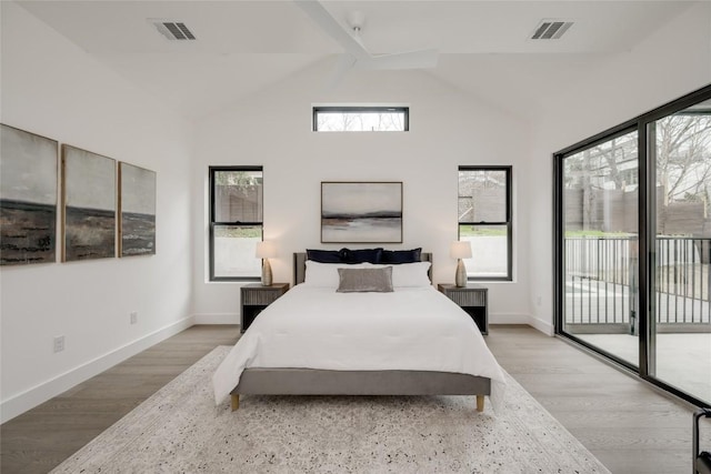 bedroom with multiple windows, access to exterior, and hardwood / wood-style floors