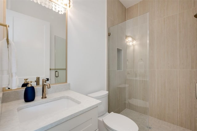 bathroom featuring vanity, a shower with shower door, and toilet