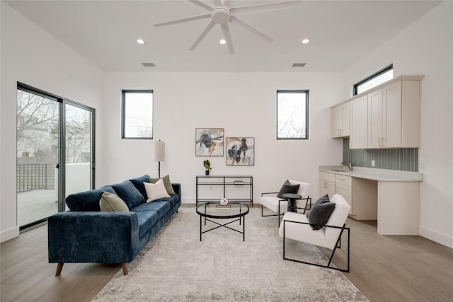 living room featuring sink, light hardwood / wood-style flooring, and ceiling fan