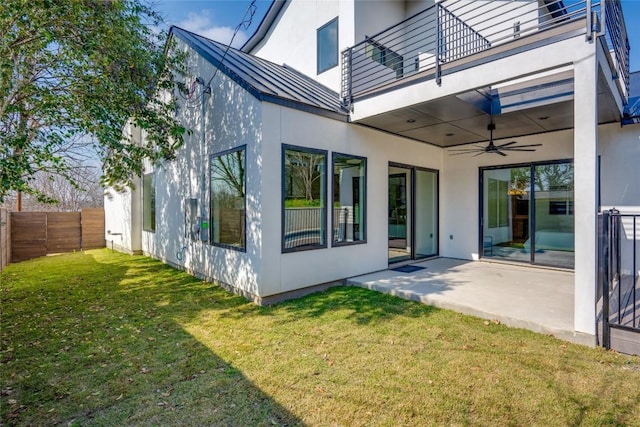 back of property featuring ceiling fan, a balcony, a patio area, and a lawn