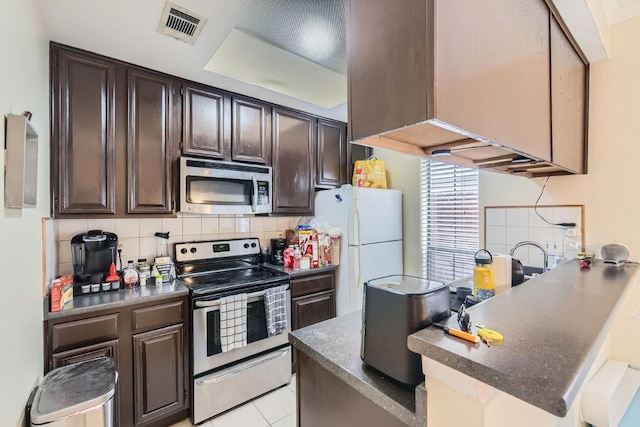 kitchen featuring appliances with stainless steel finishes, kitchen peninsula, dark brown cabinetry, and decorative backsplash