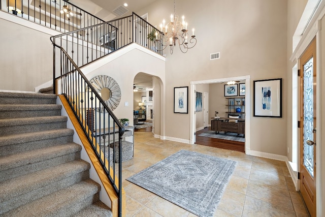 tiled foyer entrance featuring an inviting chandelier, a towering ceiling, and plenty of natural light