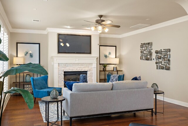 living room with dark hardwood / wood-style flooring, a fireplace, ornamental molding, and ceiling fan