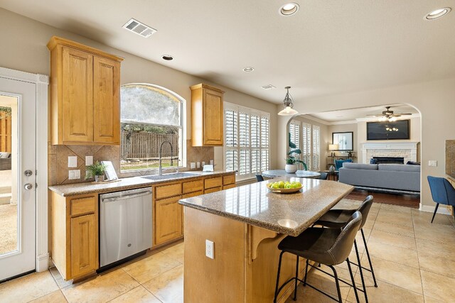 kitchen with a kitchen island, decorative light fixtures, tasteful backsplash, dishwasher, and sink