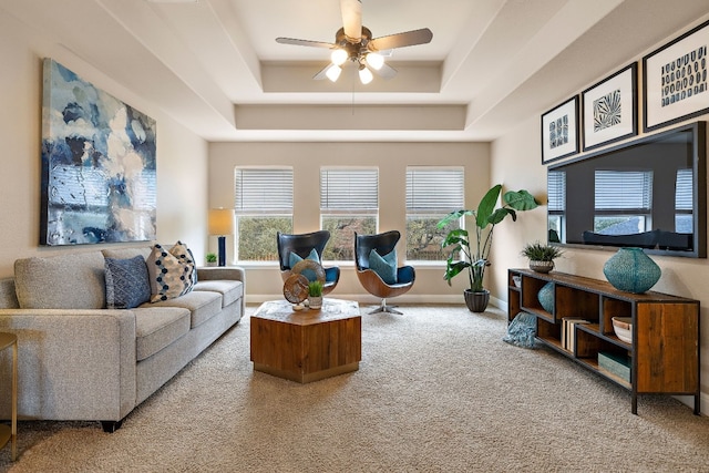 living room featuring a raised ceiling, carpet flooring, and ceiling fan