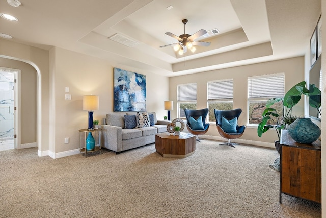 living room featuring a tray ceiling, ceiling fan, and carpet flooring